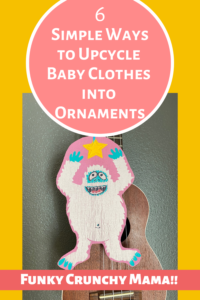 Pinterest image shows a yet ornament hanging in front of a ukelele. Article title is depicted on a coral-colored circle in white text. The title is "6 Simple Ways to Upcycle Baby Clothes into Ornaments." The poster's blog title, Funky Crunchy Mama, is along the bottom.